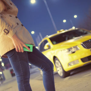 Passenger holding her cellphone and a yellow cab